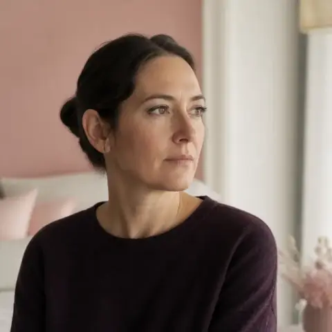 Ritratto di Livia Bartolini, capelli castani raccolti in uno chignon basso, maglia color prugna, accanto a una finestra